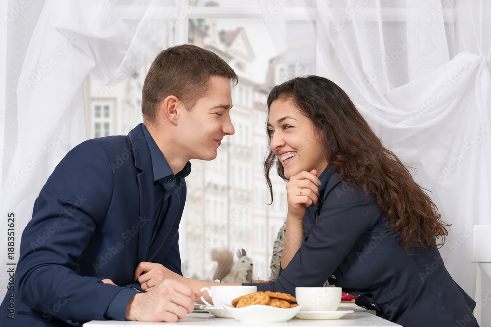 happy couple drinking coffee and talking near window with a street view - travel and love concept happy couple drinking coffee and talking near window with a street view - travel and love concept
