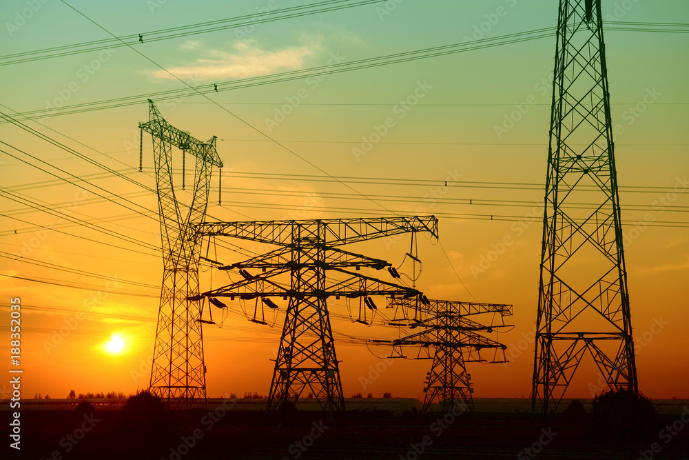 High voltage towers under the setting sun, close-up