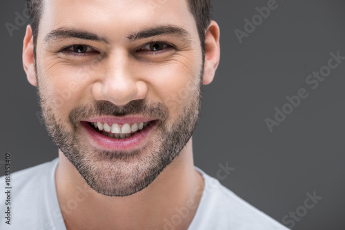 portrait of handsome smiling man looking at camera, isolated on grey