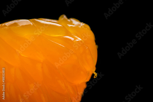 Macro shot of mandarin slice isolated on black background. Shallow depth of field. photo