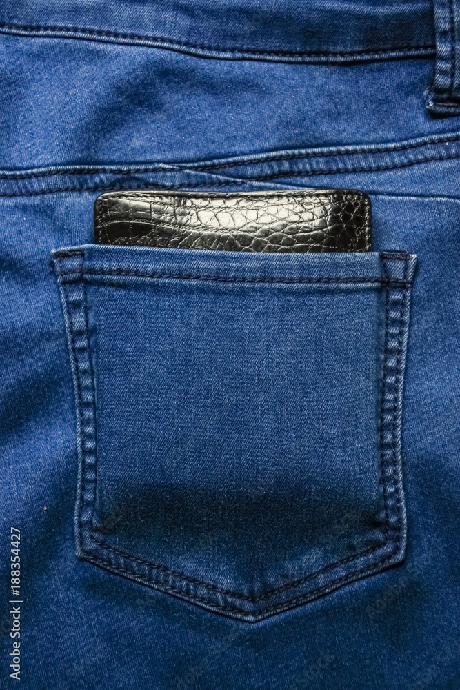 Black leather wallet in back blue jeans pocket denim background texture. Black leather wallet in back blue jeans pocket denim background texture.