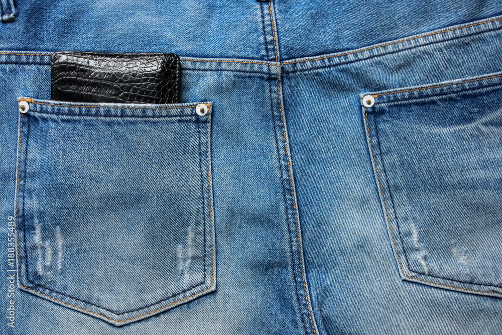 Black leather wallet in back blue jeans pocket denim background texture. Black leather wallet in back blue jeans pocket denim background texture.