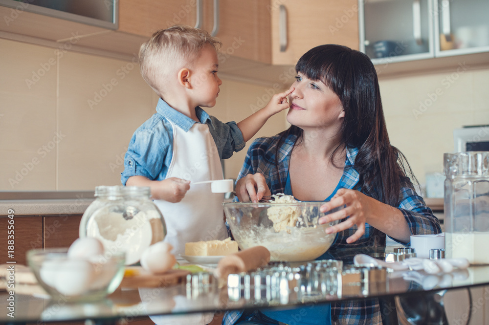 adorable son touching mother face in kitchen adorable son touching mother face in kitchen