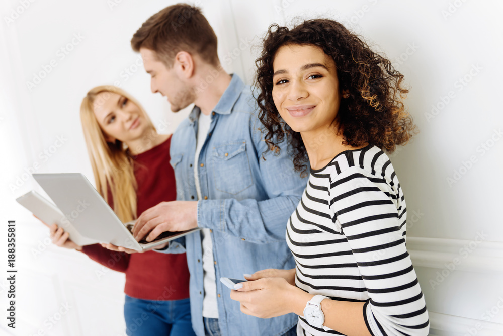 I am here. Attractive female person standing in semi position and holding telephone in both hands while looking forward I am here. Attractive female person standing in semi position and holding telephone in both hands while looking forward
