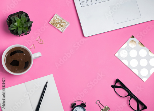 Coffee, glasses laptop and other objects on the bright pink background