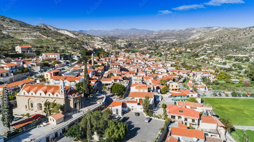 Aerial bird's eye view of Kalavasos village valley, Larnaca, Cyprus. A traditional town with ceramic roof tiles houses, a greek orthodox christian church and muslim mosque around hills from above. 