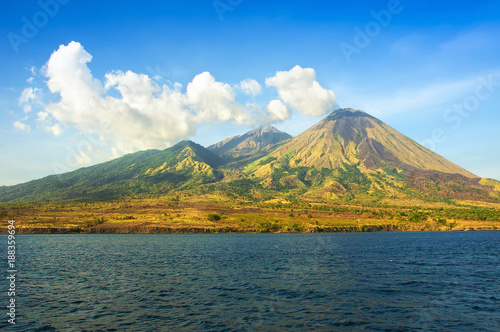 Indonesia landscape. Far island with volcanos and tropical forests among a sea. View from the water.