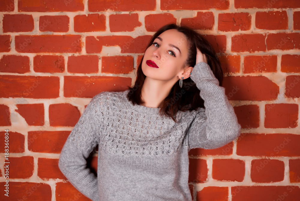 beautiful girl in the studio on a red brick happy background on holidays and enjoys a pomp