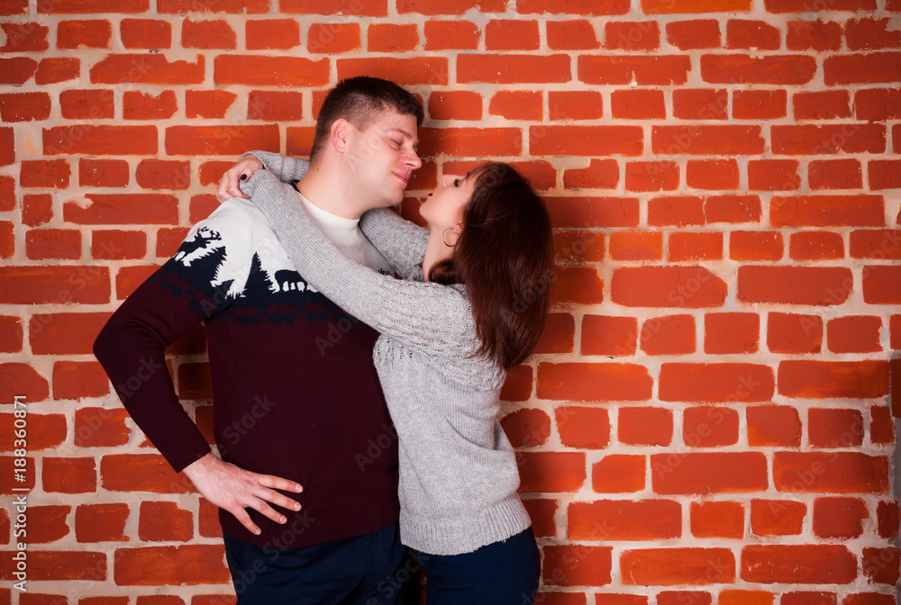 beautiful girl in the terrier on a red brick background happy for the holidays and enjoys the gift with her husband beautiful girl in the terrier on a red brick background happy for the holidays and enjoys the gift with her husband