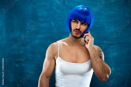 Transsexual male person wearing blue wig and female cloth talking on the phone