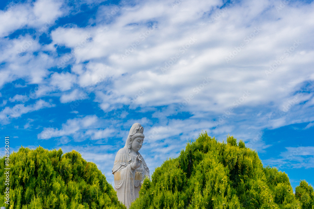 Female Buddha statue against blue sky on the background