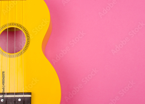 Fototapeta Body of a bright yellow ukulele guitar against a bright pink background (minimalism style), copy space on the right for your text
