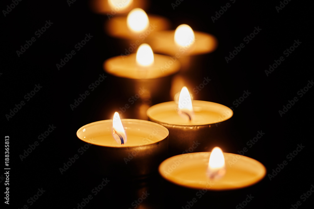 Burning votive candles on dark background Burning votive candles on dark background