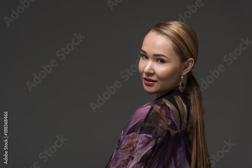 portrait of beautiful kazakh woman smiling at camera isolated on grey