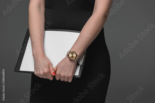 close-up partial view of businesswoman holding clipboard isolated on grey