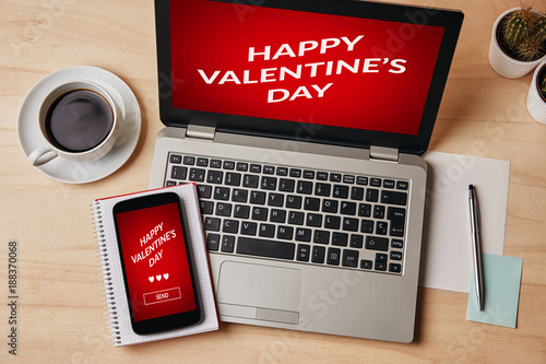 Valentine's day concept on laptop and smartphone screen over wooden table. All screen content is designed by me. Flat lay