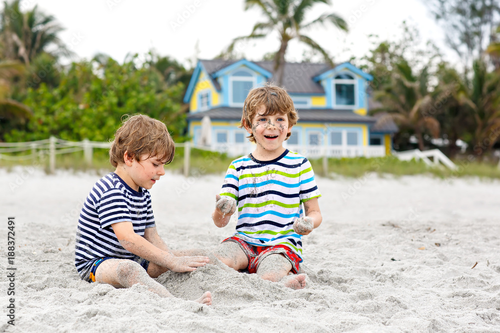 Two little kids boys having fun with building sand castle on tropical beach Two little kids boys having fun with building sand castle on tropical beach