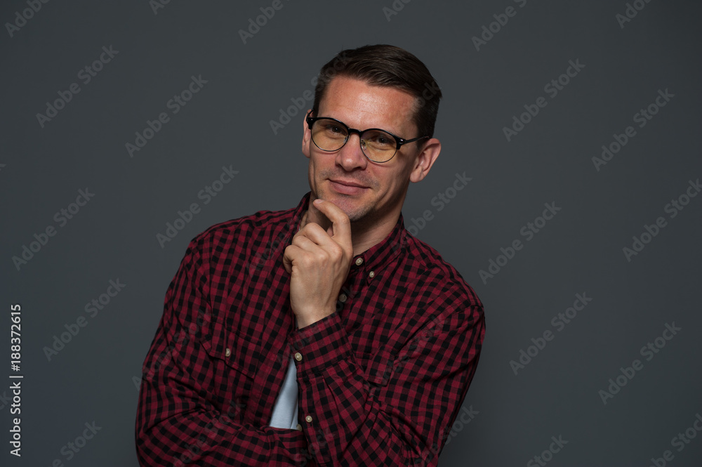 Obraz premium Portrait of successful young businessman with glasses smiling and looking at the camera on gray background