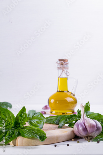 Fresh green basil with garlic and olive oil on white background