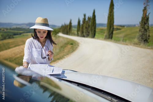 Young woman got lost in the field while driving a car and reading paper map © ZoomTeam