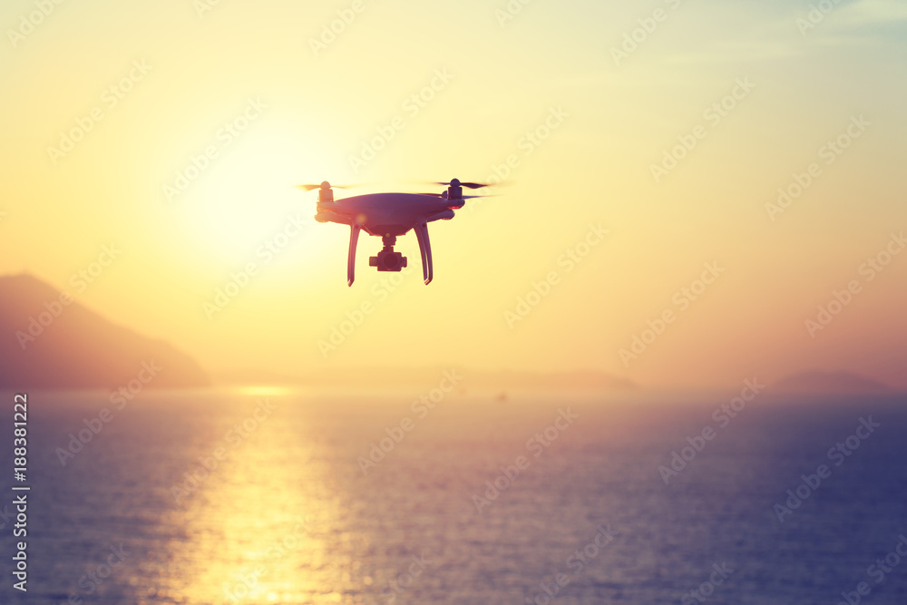 silhouette of flying drone which taking photo over sunrise sea. silhouette of flying drone which taking photo over sunrise sea.