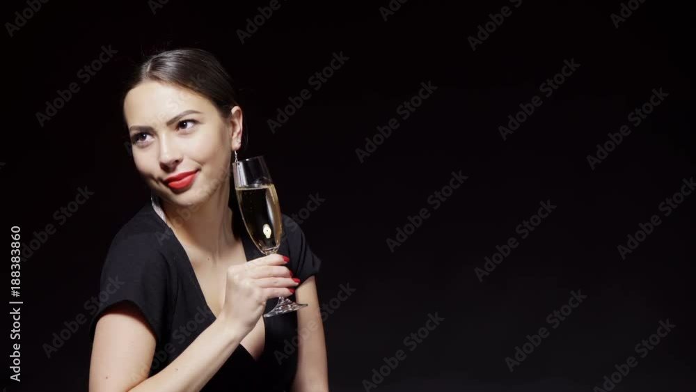 Party, drinks, holidays and celebration concept. Closeup happy smiling playful flirty woman in black dress with glass of champagne over dark background Party, drinks, holidays and celebration concept. Closeup happy smiling playful flirty woman in black dress with glass of champagne over dark background