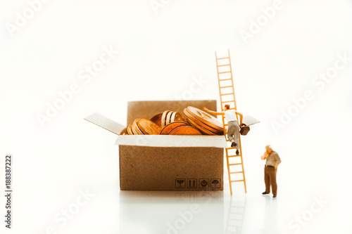 Miniature people, man climbing ladder to pick up golden coins using as business and finance concept