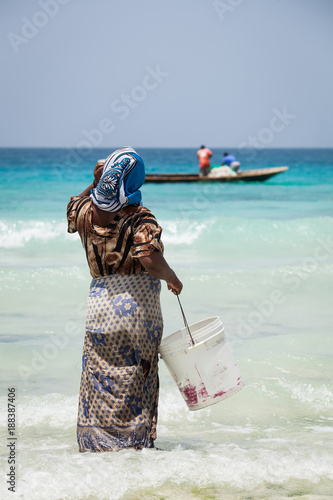 Woman waiting for fishing boat to come into shore in Stone Town, Zanzibar Island, Tanzania.