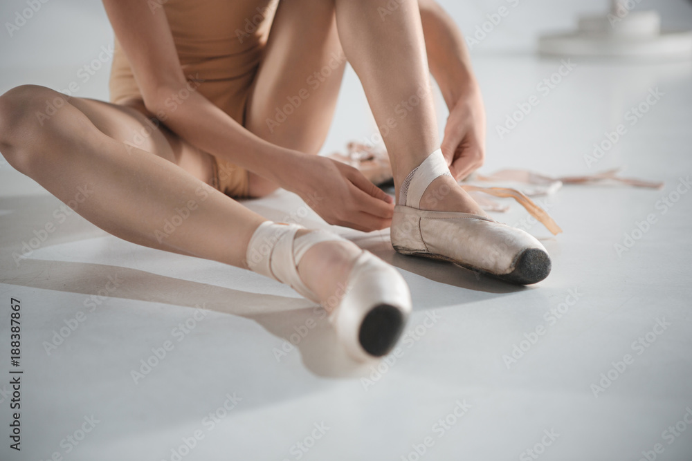 Fototapeta premium Beautiful little ballerina in blue dress for dancing puting on foot pointe shoes