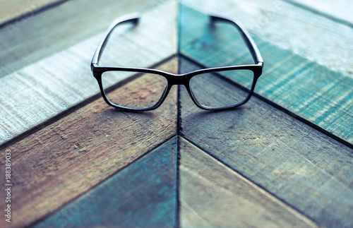 Modern black designer eyeglasses on weathered wood surface with angular pattern. photo