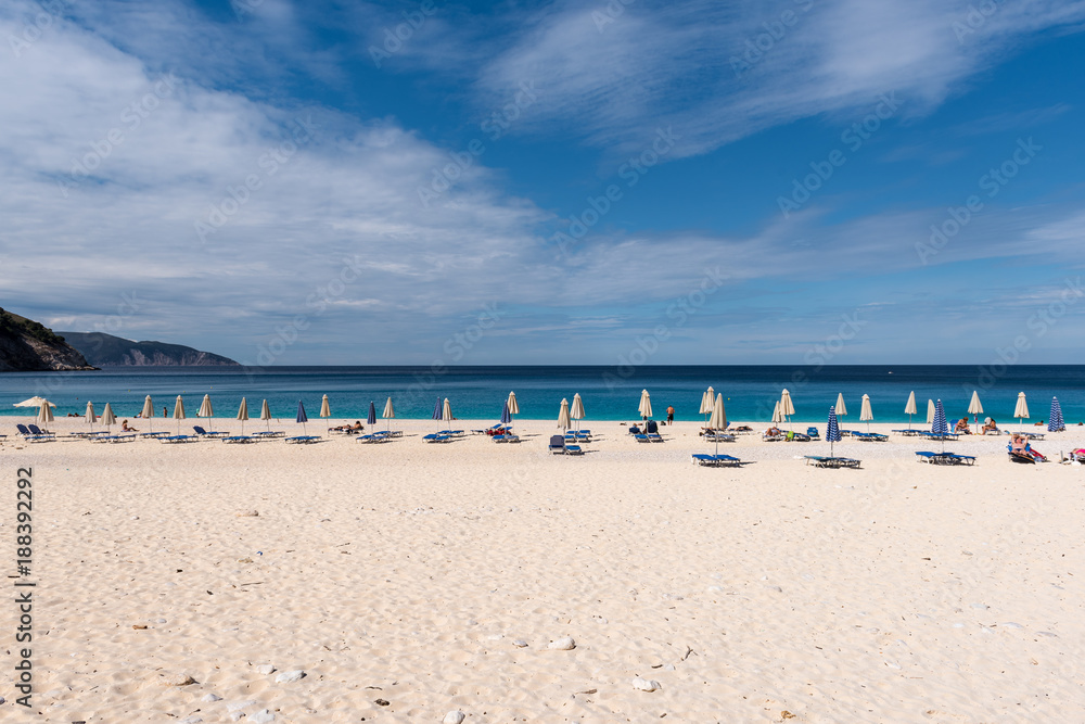Sun beds and parasols on beautiful Myrtos beach with white sand and blue sea water on Kefalonia island. Greece.