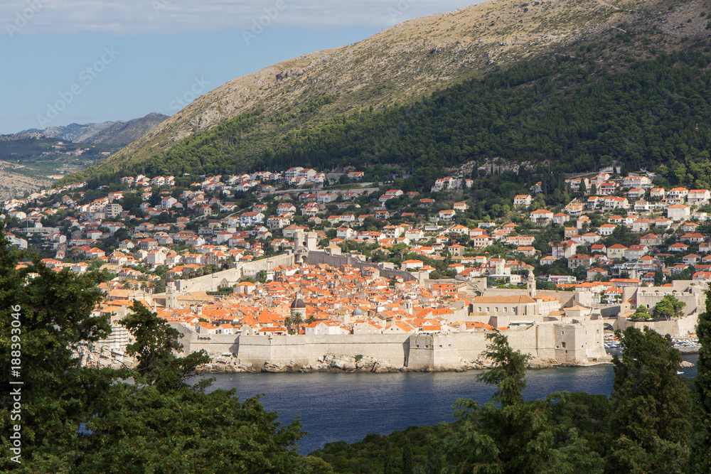 Old Town, buildings on the hillside and Mount Srd in Dubrovnik, Croatia, viewed from the lush Lokrum Island on a sunny day.