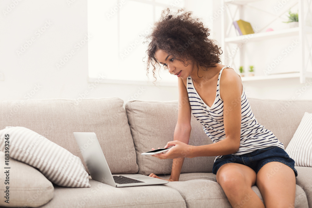 Young girl with laptop messaging on mobile Young girl with laptop messaging on mobile