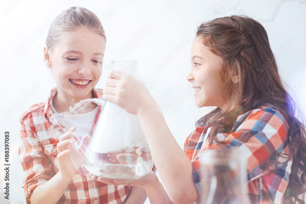 So much fun. Two young ladies getting pretty excited while holding a fuming vacuum flask and chatting about the chemical experiment held by their teacher. So much fun. Two young ladies getting pretty excited while holding a fuming vacuum flask and chatting about the chemical experiment held by their teacher.
