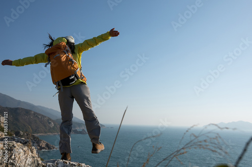 successful female hiker walking on seaside mountain peak cliff edge