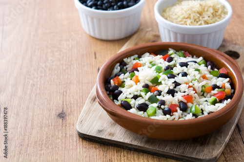Traditional cuban rice, black beans and pepper on wooden table background. Moros y cristianos.