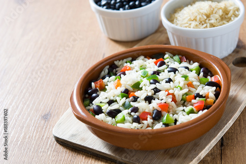 Traditional cuban rice, black beans and pepper on wooden table background. Moros y cristianos.