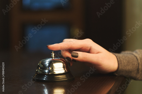 Woman ringing hotel reception service bell closeup