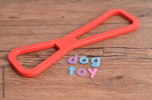 A red rubber tug of war toy for a dog with the word dog toy