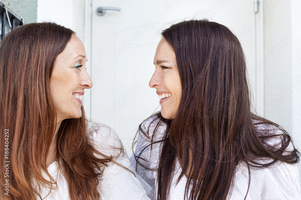 Two brunettes looking at each other and smiling Two brunettes looking at each other and smiling