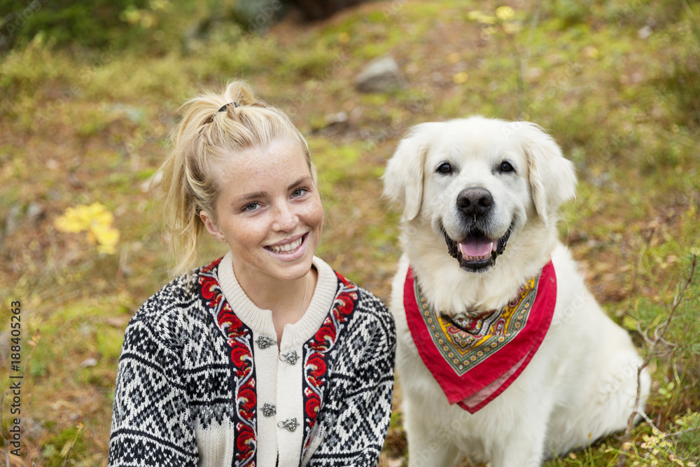 Portrait of young smiling woman sitting in meadow with dog Portrait of young smiling woman sitting in meadow with dog