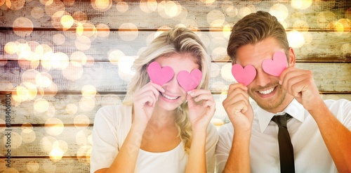 Composite image of attractive young couple holding pink hearts