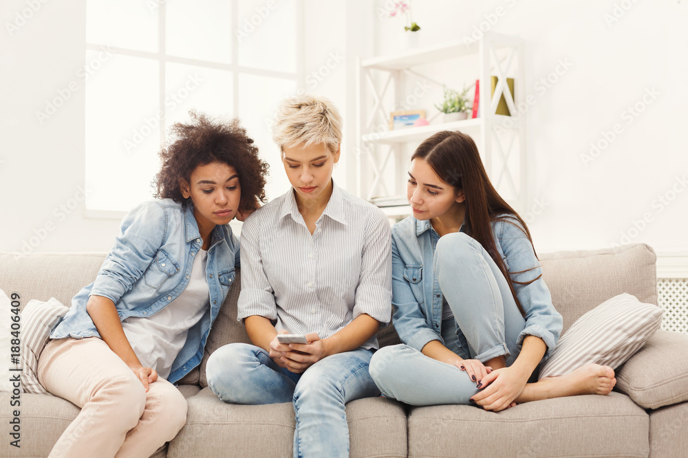 Three female friends using smartphones at home Three female friends using smartphones at home