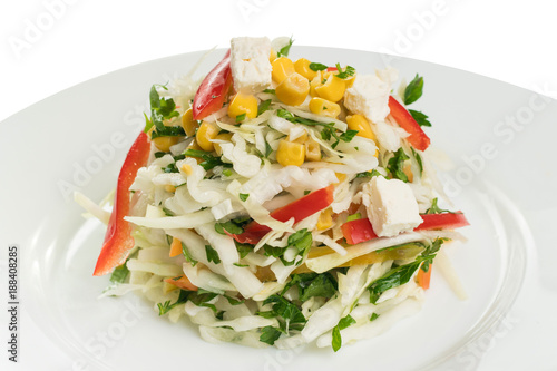 salad of white cabbage with sweet pepper, corn and cheese on a white plate