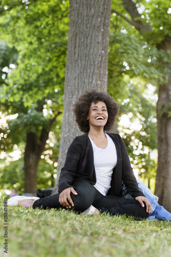 Portrait of young woman sitting outdoors on grass and smiling