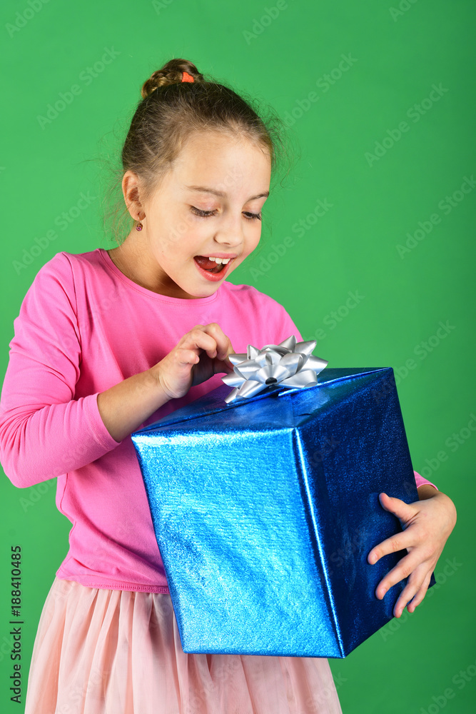 Child with curious smiling face poses with present Child with curious smiling face poses with present
