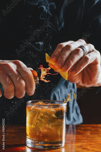 Midsection of bartender heating peel while preparing drink at bar photo
