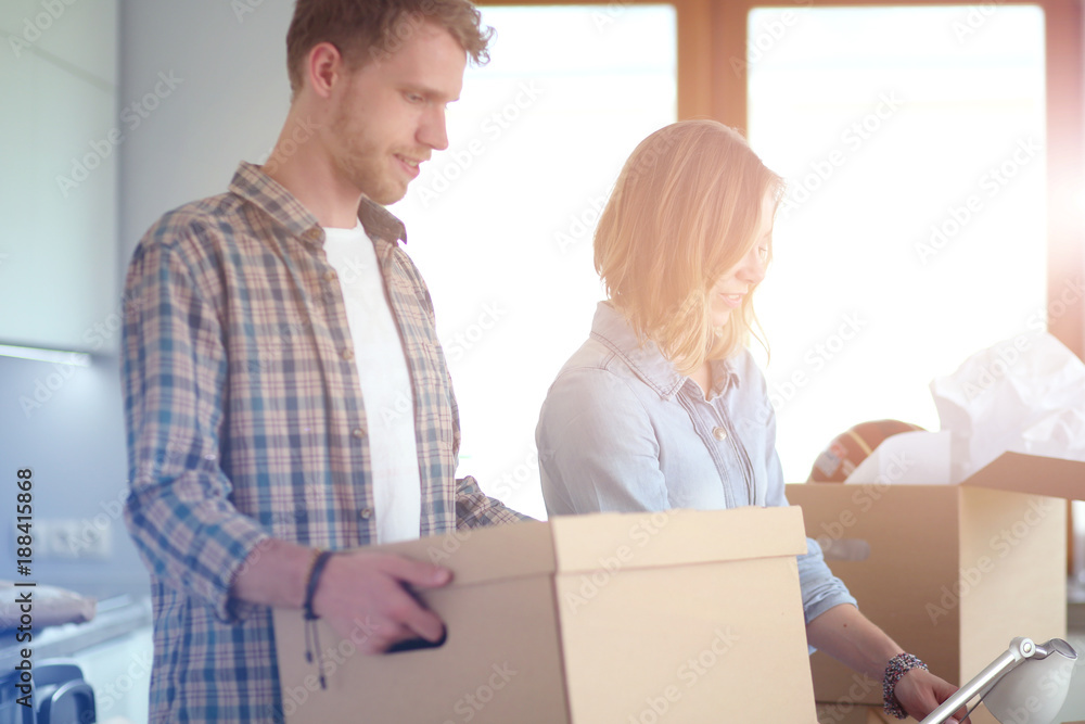 Couple unpacking cardboard boxes in their new home. Young couple. Couple unpacking cardboard boxes in their new home. Young couple.