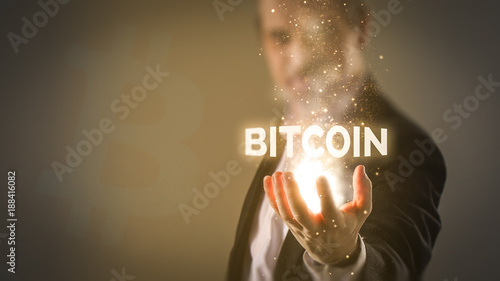 making money with bitcoin - Business man holding a glowing word Bitcoin with energy sparkles coming from hand photo