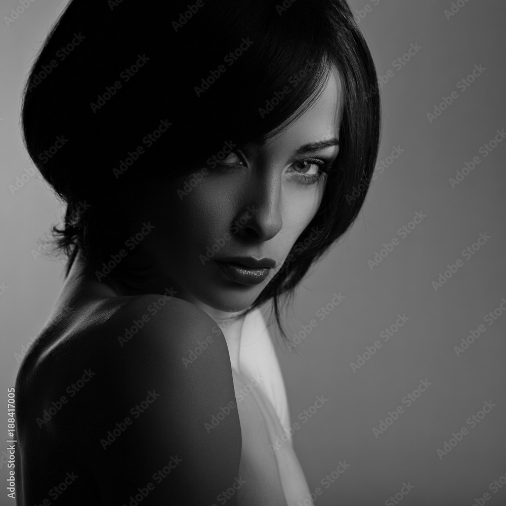 Sexy beautiful makeup woman with short hair style, red lipstick on dark shadow background. Closeup portrait. Black and white portrait